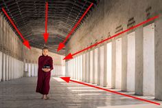 a monk is standing in the middle of an empty building with red arrows pointing to his left