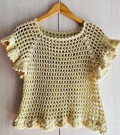 a crocheted top hanging on a wooden hanger