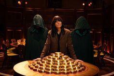 a woman standing in front of a table filled with gold cups and candles on top of it