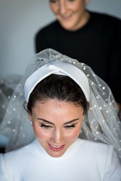 a woman is getting her hair done with a veil over her head and smiling at the camera