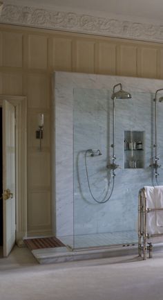 a bathroom with marble walls and flooring next to a shower stall in the middle of the room