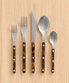 four forks, two spoons and one knife on a wooden surface with holes in it