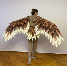 a woman standing in front of a white wall with wings on it