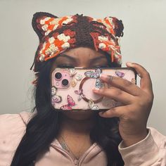 a woman taking a selfie with her phone wearing a knitted cat ears hat