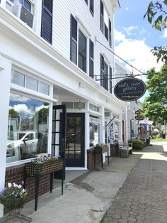 the outside of a building with many windows and flowers in pots on the side walk