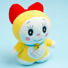 a small yellow stuffed animal with a red bow on its head and eyes, sitting in front of a blue background