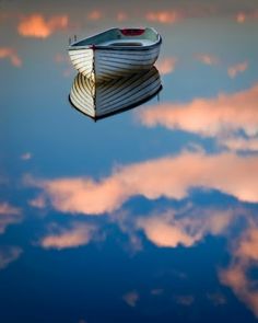 a boat floating on top of a body of water with clouds in the sky behind it