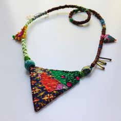 a multicolored necklace is displayed on a white surface with beads and other accessories