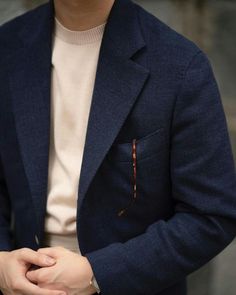 a man in a blue jacket and white shirt is holding his hand on his pocket