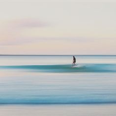 a man riding a wave on top of a surfboard in the ocean at sunset