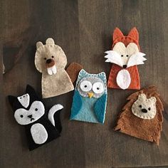 four felt animal finger puppets sitting on top of a wooden table