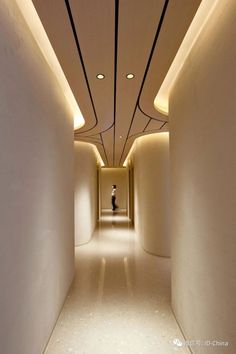 an empty hallway with white walls and lights on the ceiling is lit by recessed lighting