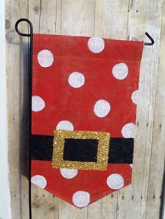 a red and white polka dot santa clause flag hanging on a wooden door with a black handle