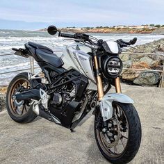 a white and black motorcycle parked next to the ocean