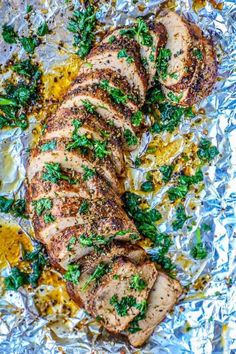 sliced pork on foil with parsley and lemon zest in the middle, ready to be served