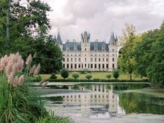 a large building sitting on top of a lush green field next to a lake in front of it