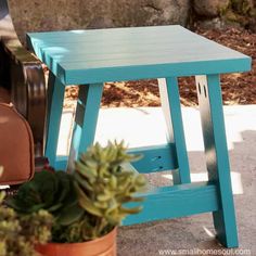 a small blue stool sitting next to a potted plant