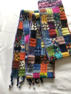 two crocheted scarfs laying on top of each other