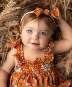 a baby girl with blue eyes wearing an orange dress