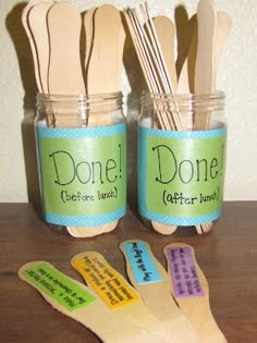 wooden utensils and spoons in jars with words written on them, sitting on a table