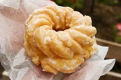 a donut that is sitting on top of wax paper in someone's hand