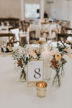 the table is set up with candles and flowers in vases on top of it