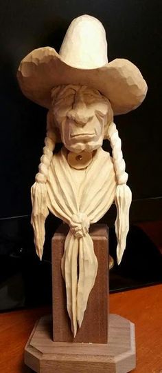 a wooden carving of an old man wearing a cowboy hat