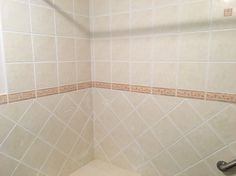 a white tiled shower stall with handrails and tile walls in a bathroom area