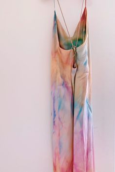 a tie - dyed dress hanging on a wall with clothes pins attached to the hanger