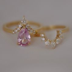 two gold rings with an oval shaped pink stone and small white diamonds on each ring