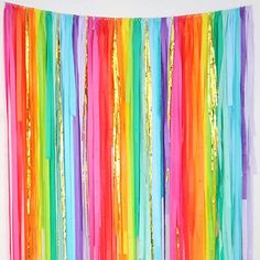 multicolored streamers hanging from the ceiling in front of a white wall and floor