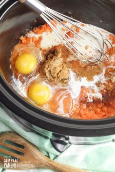 two eggs are being whisked in the crock pot with meat and spices