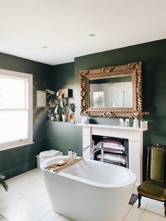 a bath tub sitting next to a fireplace in a bathroom with green walls and white tile flooring