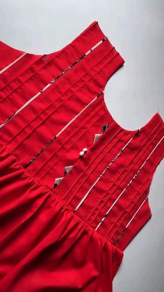 a piece of red fabric is being sewn together with pins and needles on it