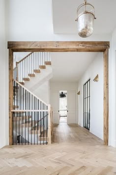 an empty room with wooden floors and stairs leading to the second floor, along with a chandelier