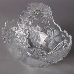 a clear glass bowl sitting on top of a white table next to a gray wall