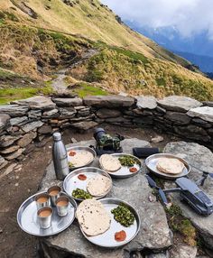 an outdoor table with food on it in the mountains