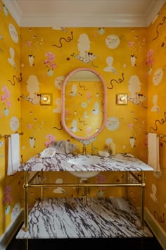 a bathroom with yellow wallpaper and pink mirror above the sink in front of it