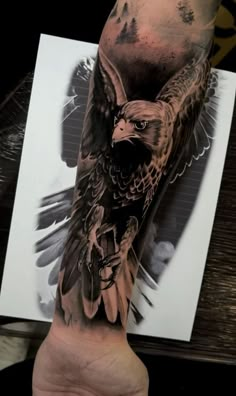 an eagle tattoo on the left arm and hand is shown in black and grey ink