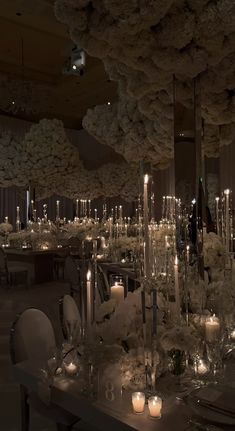 a table with candles and flowers on it in a room filled with tables, chairs and chandeliers