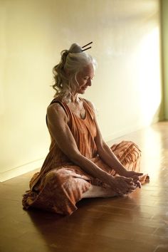 an older woman sitting on the floor with her legs crossed