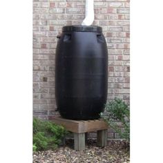 a large black barrel sitting in front of a brick wall