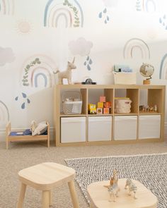 a child's playroom with toys and bookshelves on the floor in front of a rainbow wallpaper