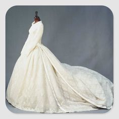 a white wedding dress on display in front of a gray background