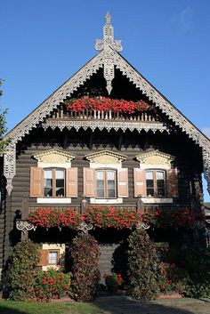 an old wooden house with flowers growing on the windows