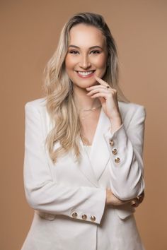 a woman in a white suit posing for the camera with her hand on her chin