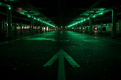 an empty parking garage at night with green lights