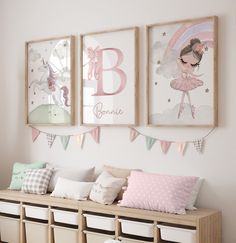 three framed pictures hang on the wall above a bench with pillows and storage bins