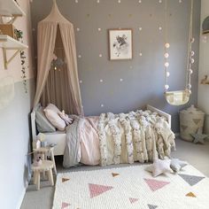 a child's bedroom with pink and gray decor, including a bed canopy over the crib