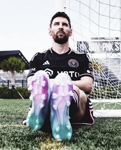 a man sitting on the ground in front of a soccer goal with his feet up